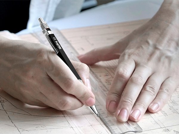 Person's hands using a 2mm mechanical pencil and ruler on a blueprint or technical drawing.