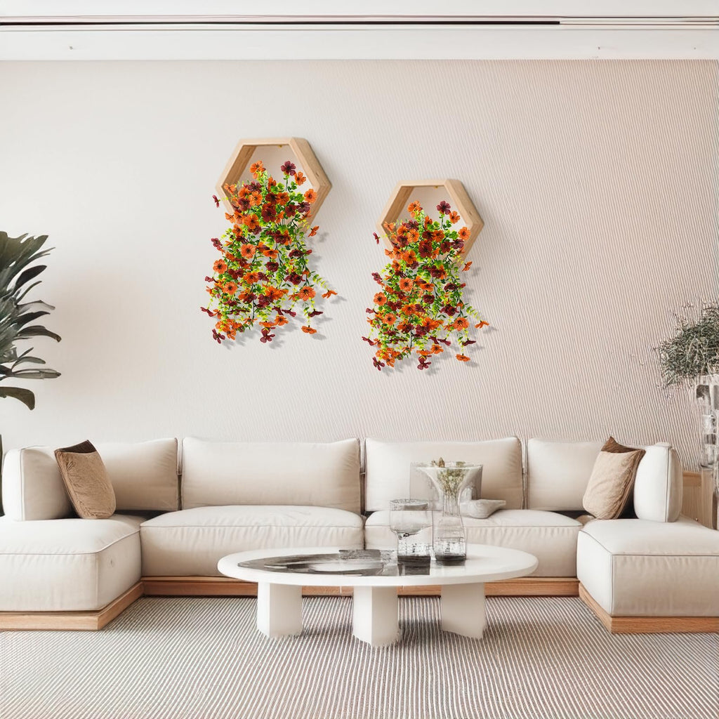 Two hexagonal wall shelves with faux silk daisy flowers and eucalyptus leaves cascading down, displayed above a sectional sofa.