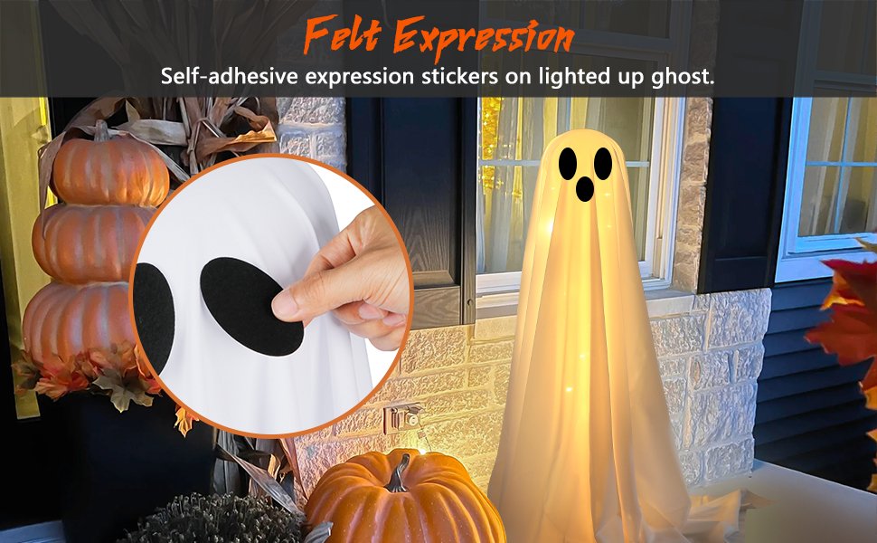 Lighted white cloth ghost decoration with felt expression stickers on a porch with pumpkins and fall leaves.