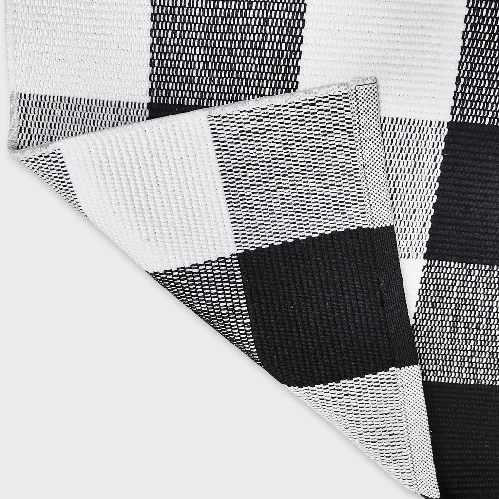 Black and white buffalo plaid woven cotton rug folded to show texture and underside