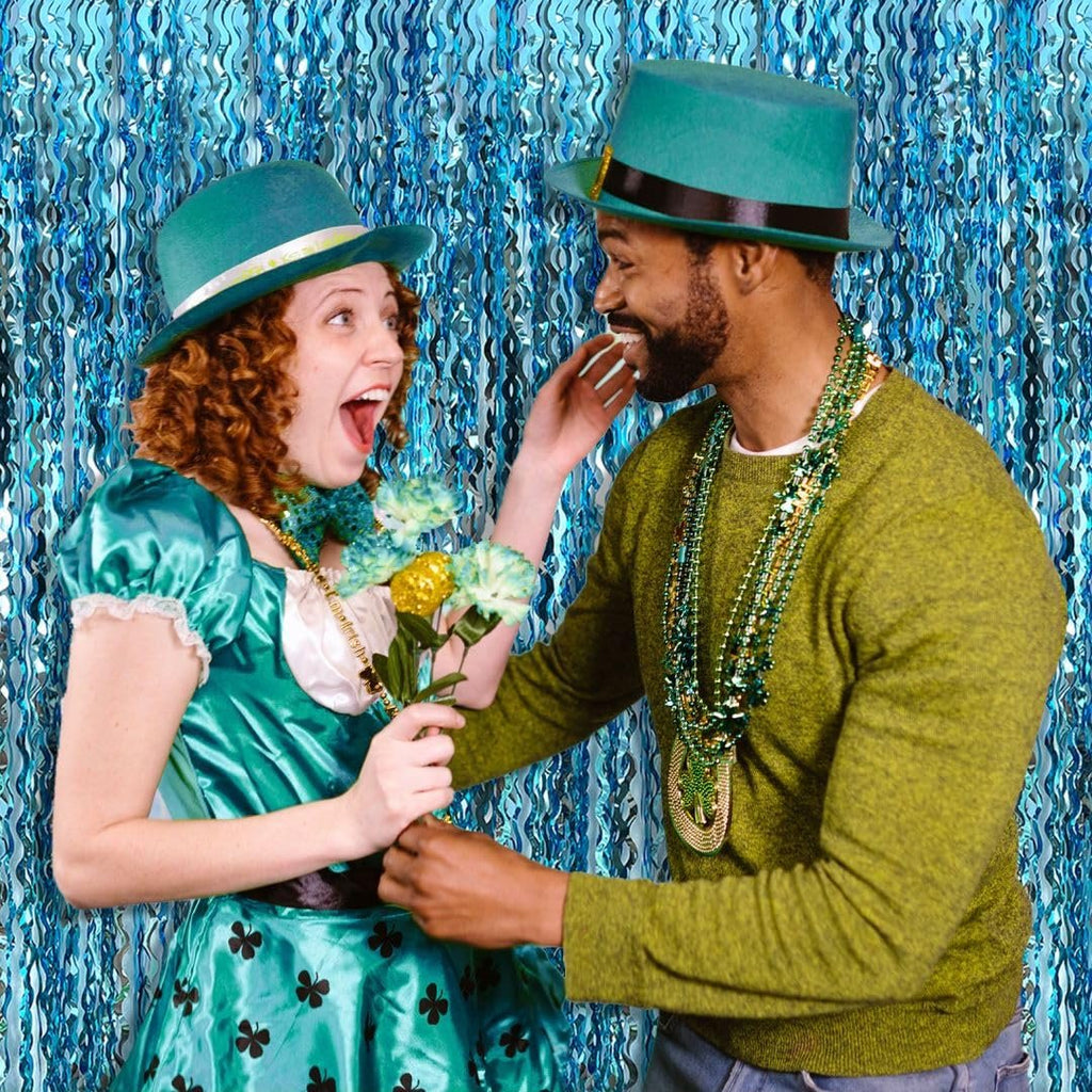 Couple celebrating St. Patrick's Day in front of a blue fringe backdrop, woman holds flowers
