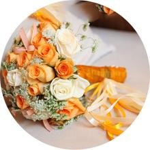 Wedding bouquet with orange and cream roses, greenery, and satin ribbons
