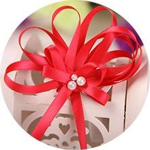 Red satin ribbon tied in a bow with three small pearls on a white decorative box