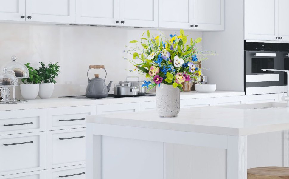 Mixed pansy wildflower bouquet in a speckled vase on a kitchen island
