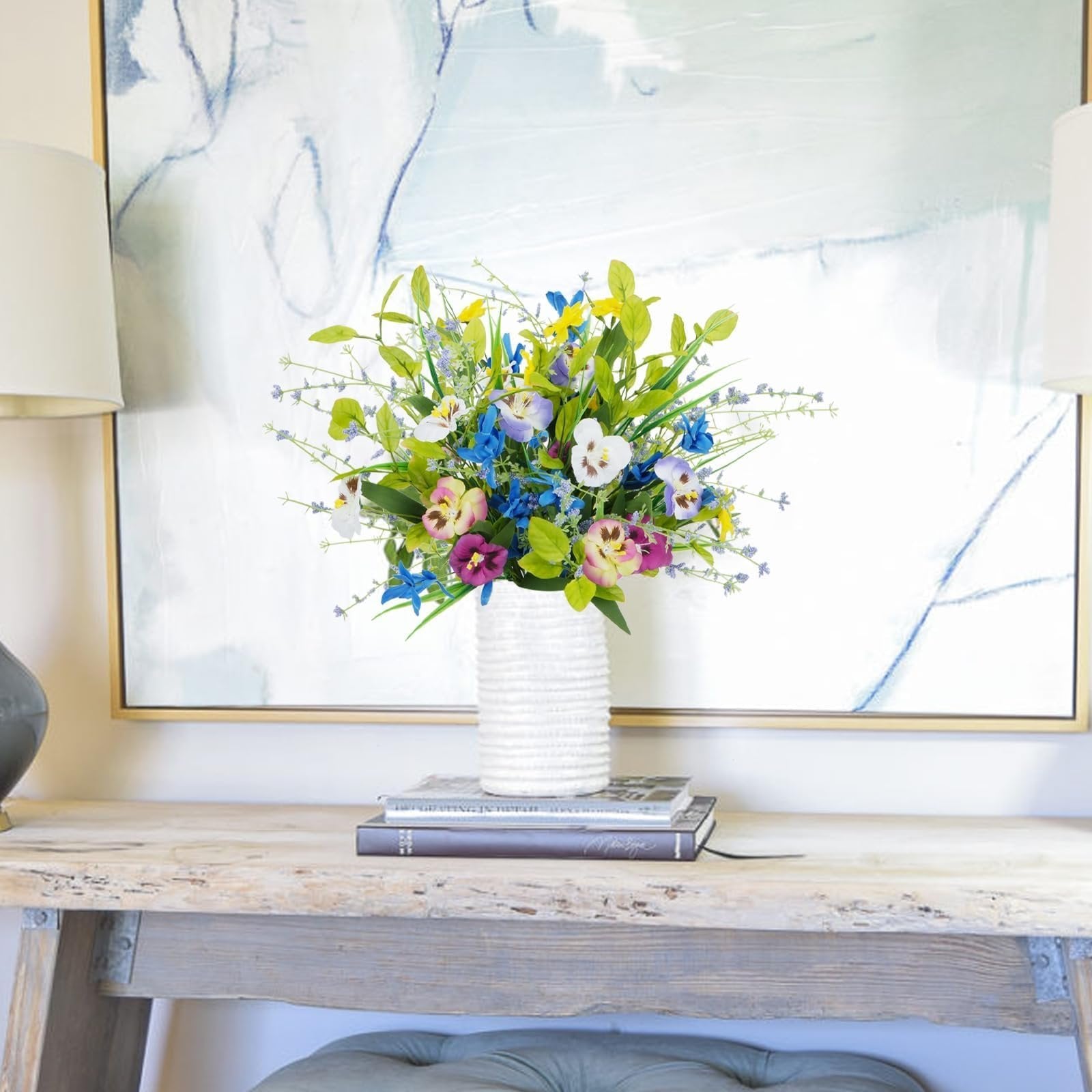 Mixed pansy and wildflower bouquet in a white textured vase on a rustic console table