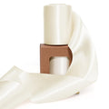 Two spools of ivory double-faced satin ribbon on a brown cardboard box, with ribbon unfurled in foreground