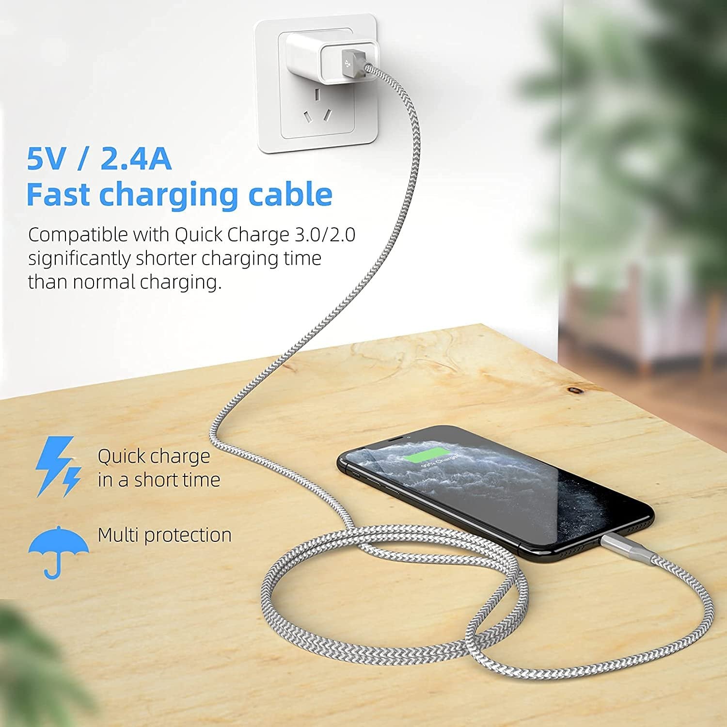 Braided grey and white charging cable plugged into a phone and wall adapter on a wooden surface.
