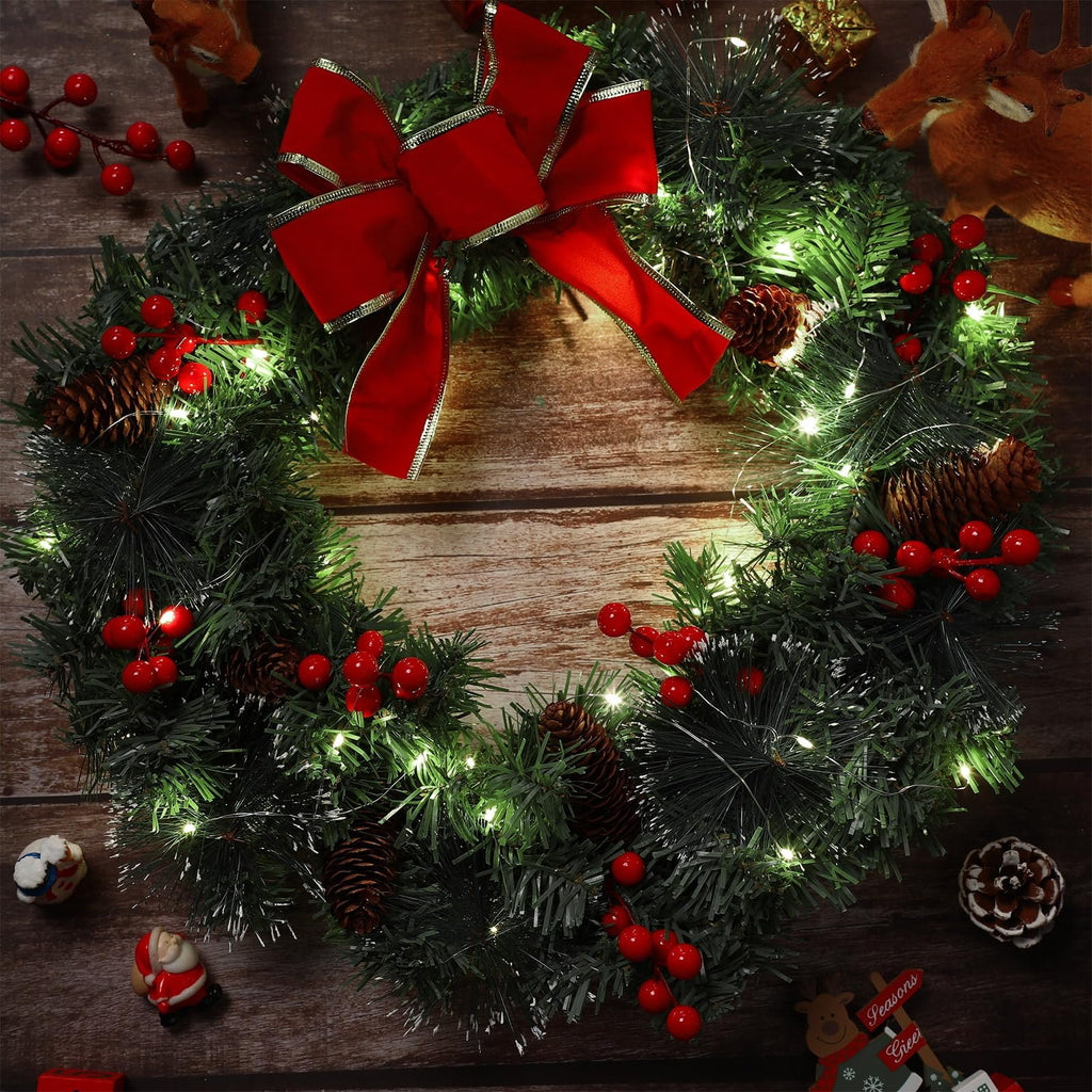 Christmas wreath with red bow, pine cones, berries, and 50 LED lights on a wooden background with decorative reindeer and Santa figures.