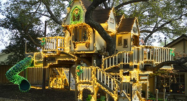 Treehouse decorated with warm white and green fairy string lights for holiday display