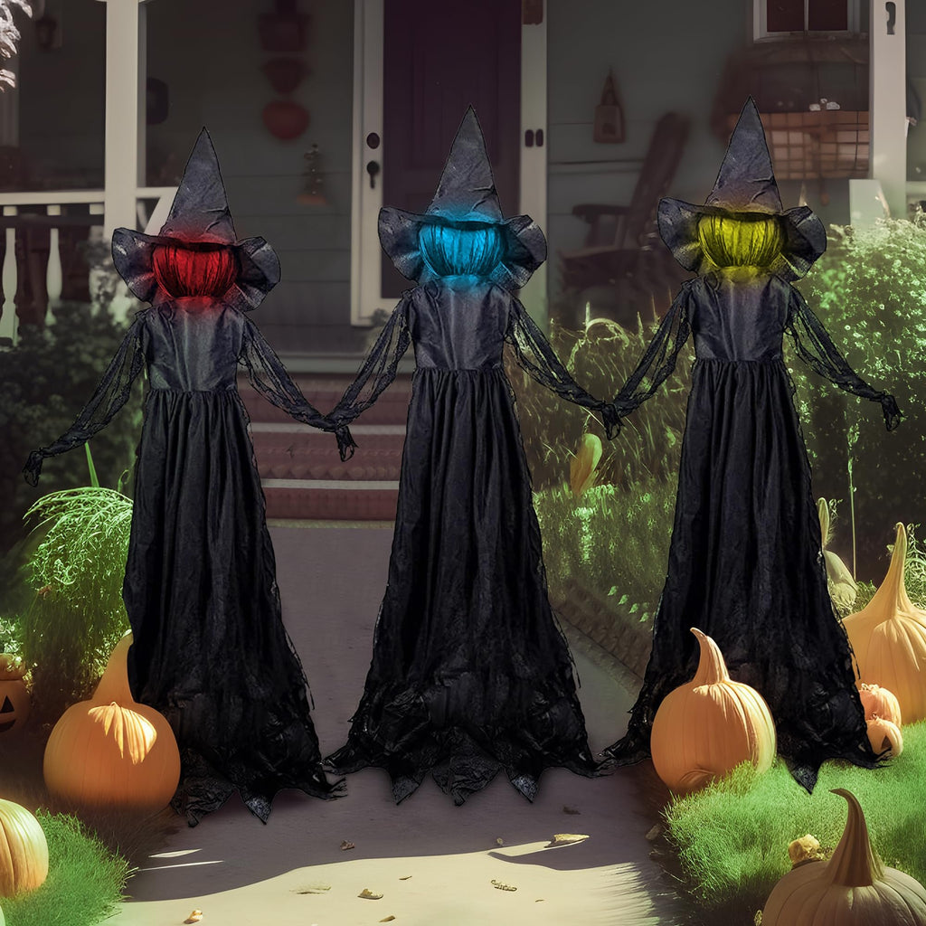 Three light-up flying witch yard stakes with flashing LED heads stand in front of a house with pumpkins