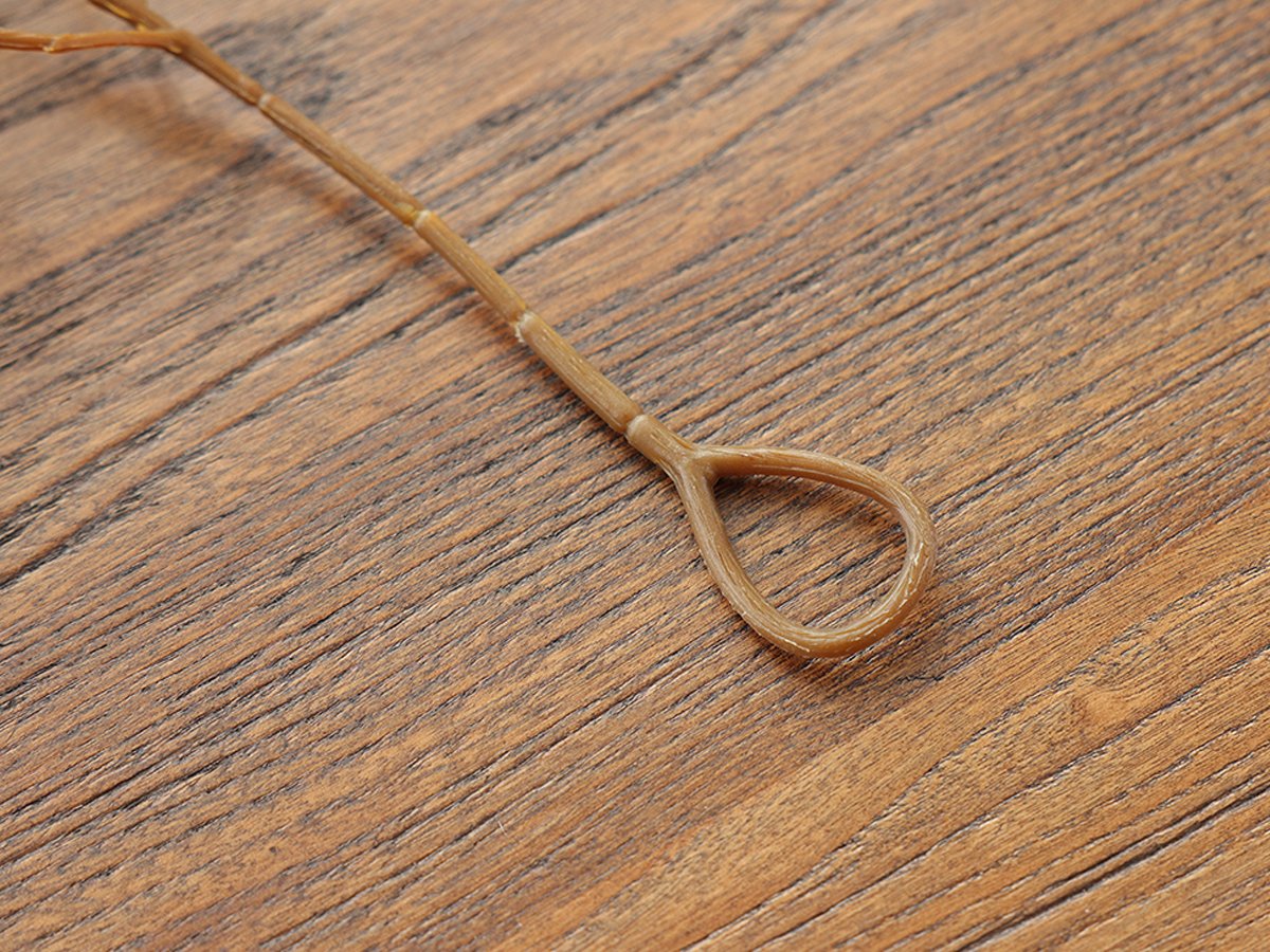 Close-up of an artificial ficus vine garland stem with a loop for hanging, on a wooden surface.