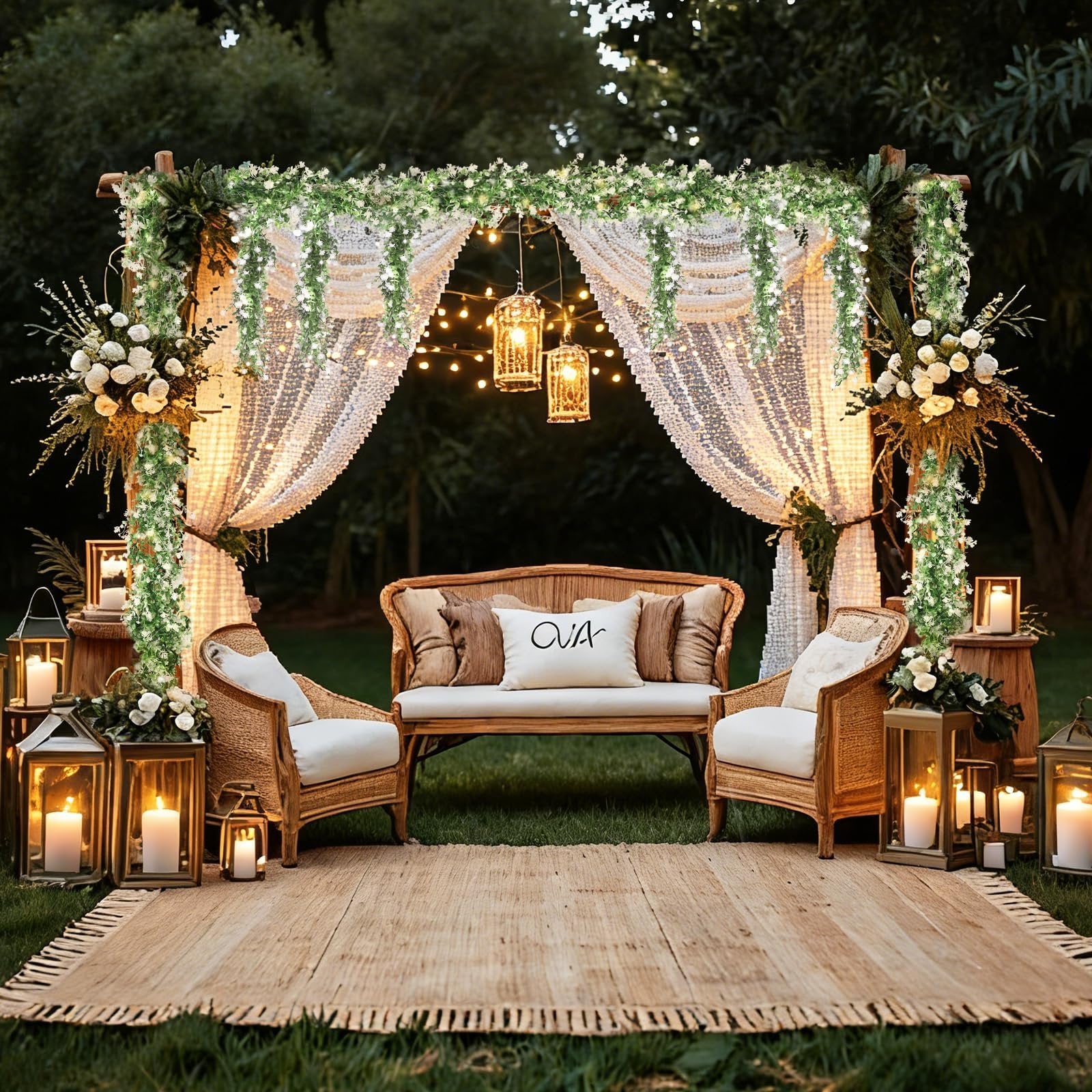 Outdoor wedding arch decorated with artificial eucalyptus garland, fairy lights, curtains, and lanterns, with seating area.
