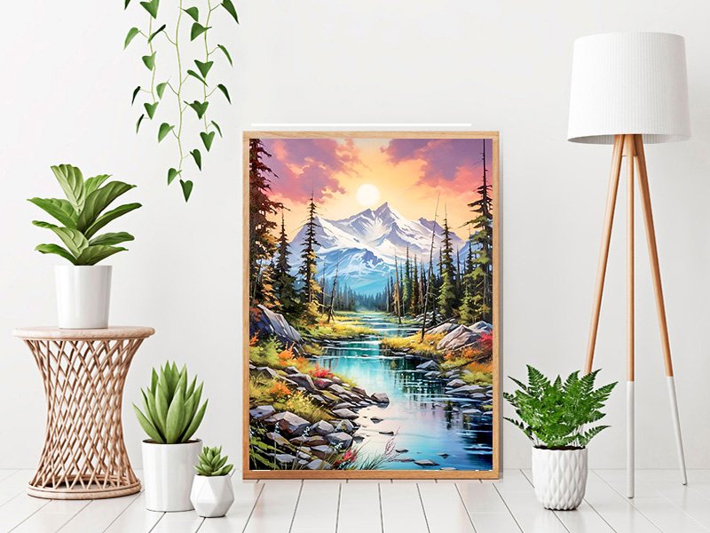 Framed diamond painting kit showing a mountain landscape with a river at sunset, displayed in a room with plants and a lamp.