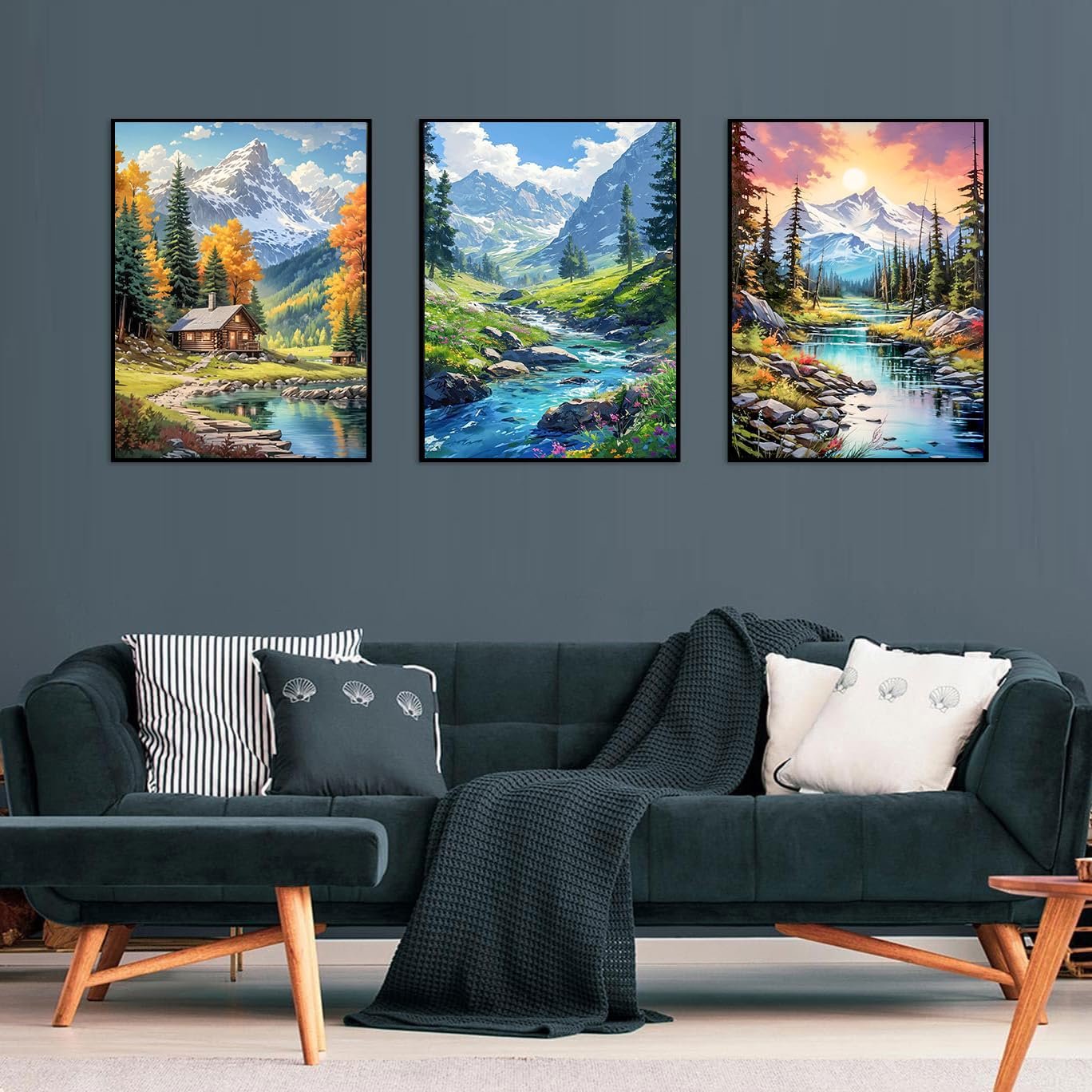 Three framed diamond painting kits depicting mountain landscapes with cabins and rivers, displayed on a wall above a sofa.