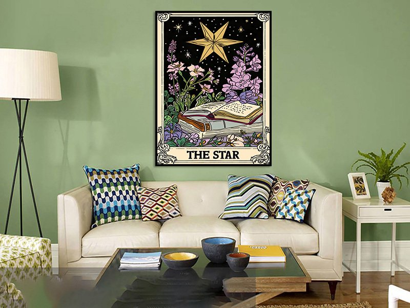 Tarot card art depicting 'The Star' with a large star, flowers, and open books, displayed on a wall above a sofa.