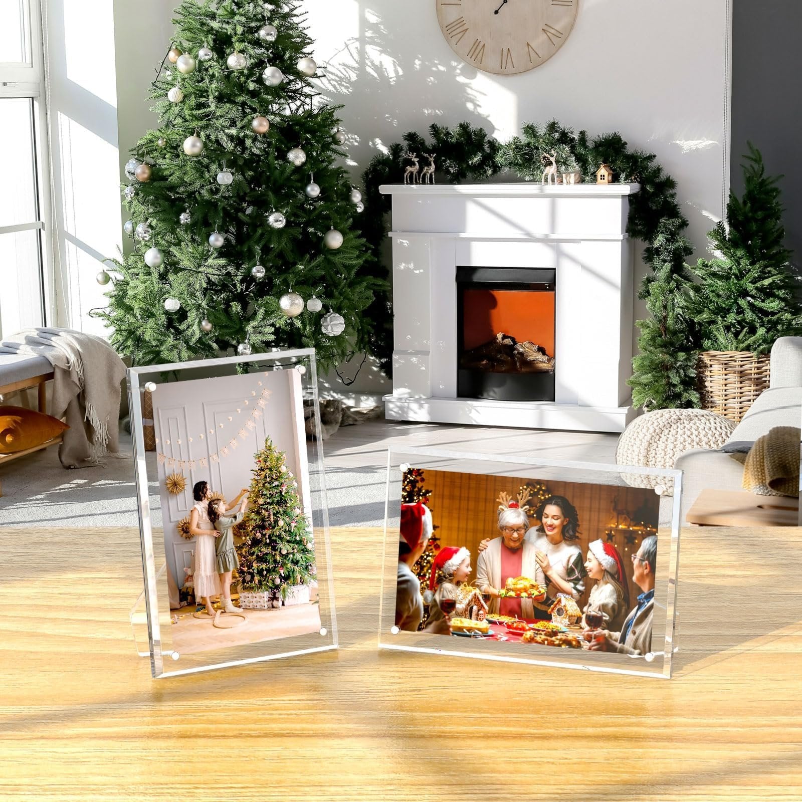Two clear acrylic picture frames displaying Christmas family photos on a wooden table, with a decorated Christmas tree and fireplace in the background.