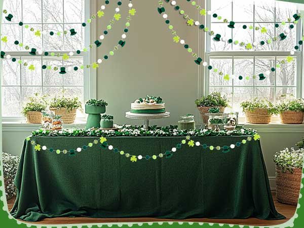 St. Patrick's Day table setting with green tablecloth, cake, and shamrock and leprechaun hat garlands hanging.