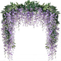 Artificial purple wisteria vine garland with green leaves draped over a white background