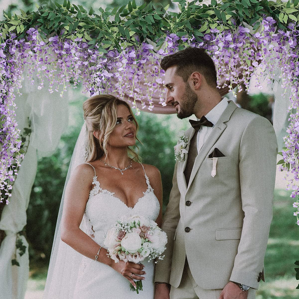 Bride and groom under artificial wisteria vine garland at wedding ceremony