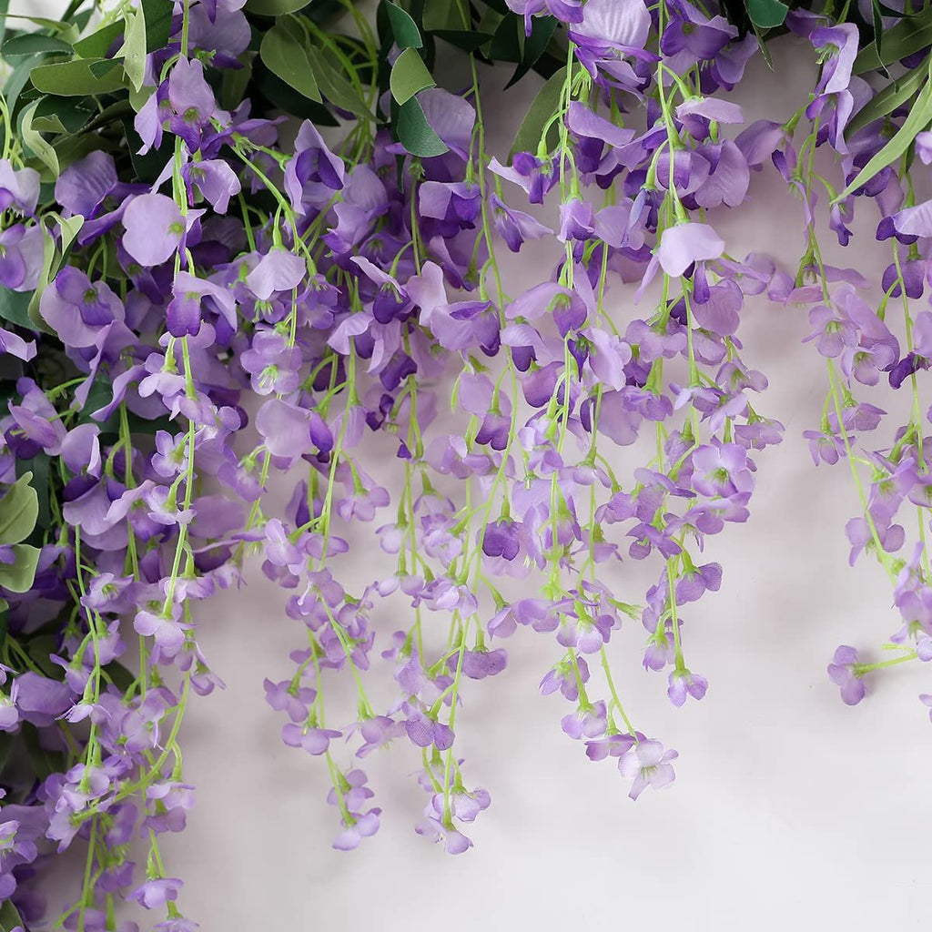 Artificial purple wisteria vine garland with green leaves cascading against a white background.