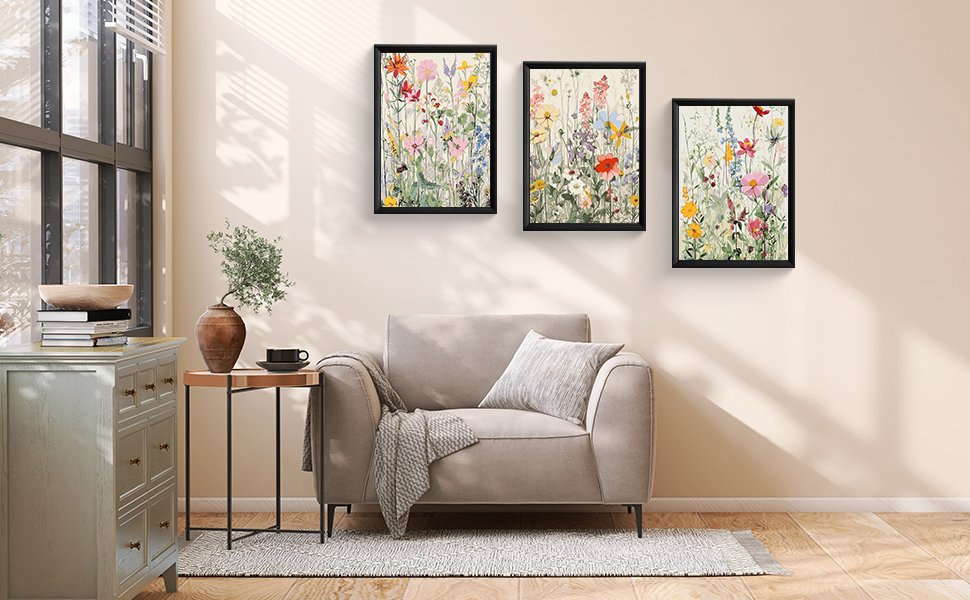 Three framed wildflower paintings displayed on a wall above a sofa in a living room setting.