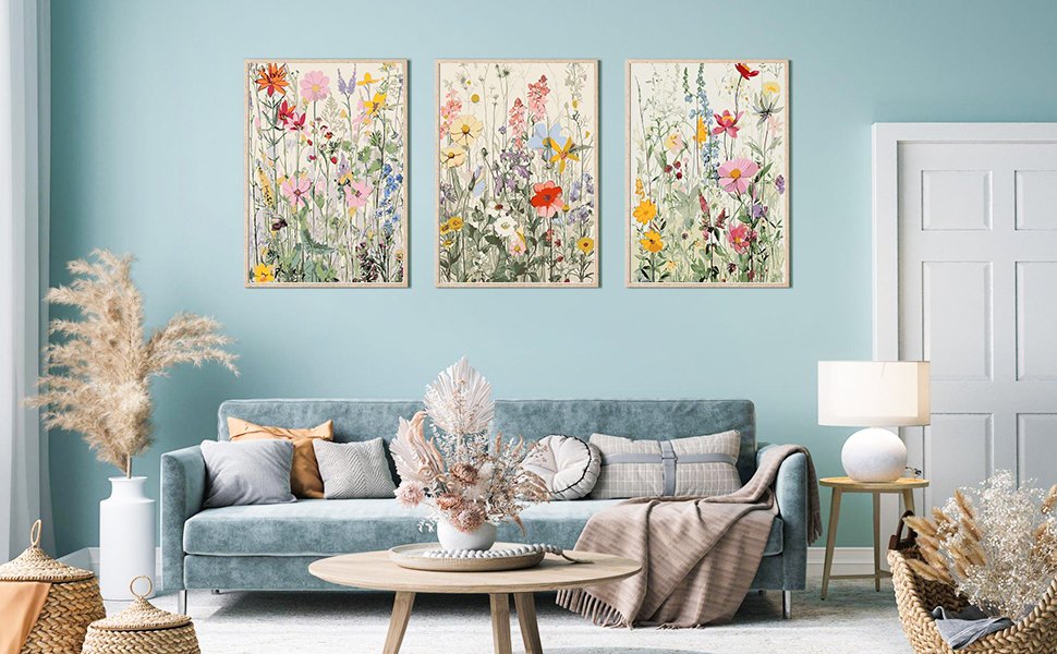 Three framed wildflower paint by numbers art pieces hanging above a blue sofa in a living room.