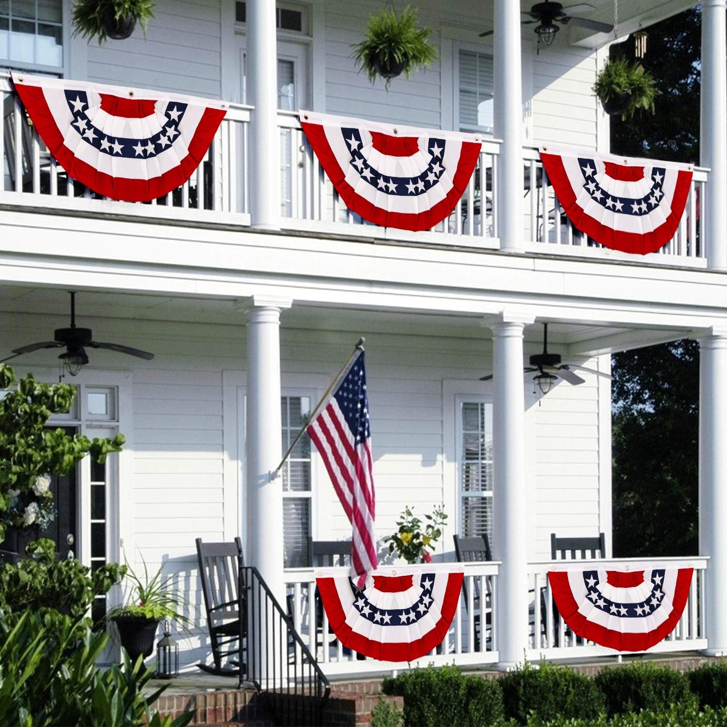 American pleated fan flags displayed on a white house porch with an American flag and rocking chairs.