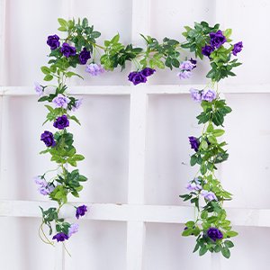 Artificial purple and light purple rose flower garland with green leaves draped over a white grid background