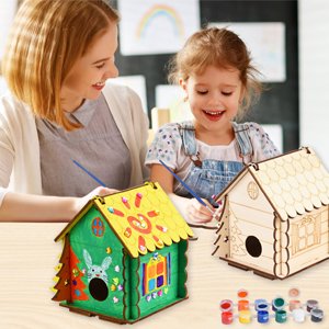 Mother and daughter crafting wooden birdhouses with paints and brushes
