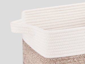 Close-up of a woven storage basket with handles, showing the textured rope material and cream-colored interior lining.