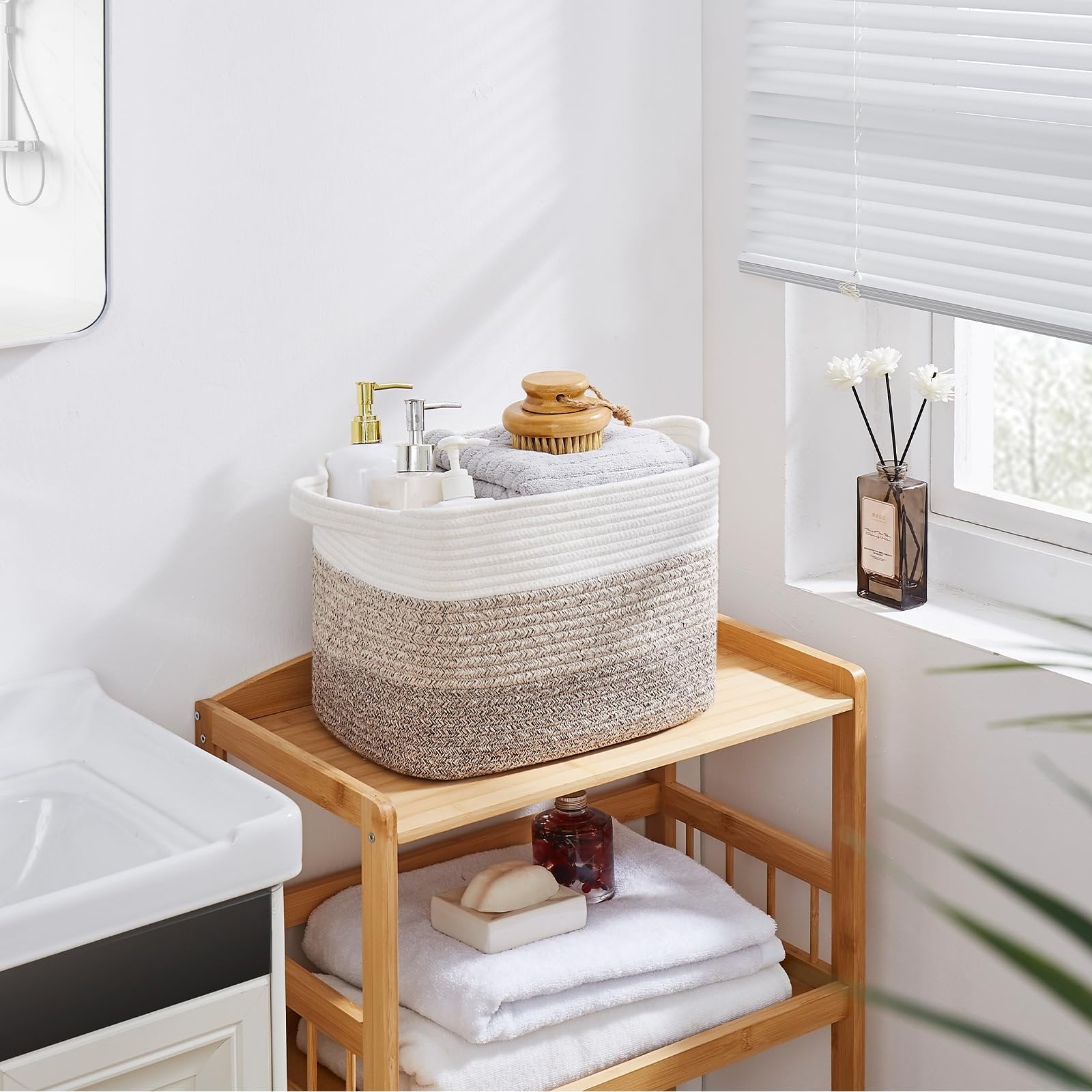 Woven storage basket with gradient yellow and white pattern filled with towels and soap dispensers on a wooden shelf.