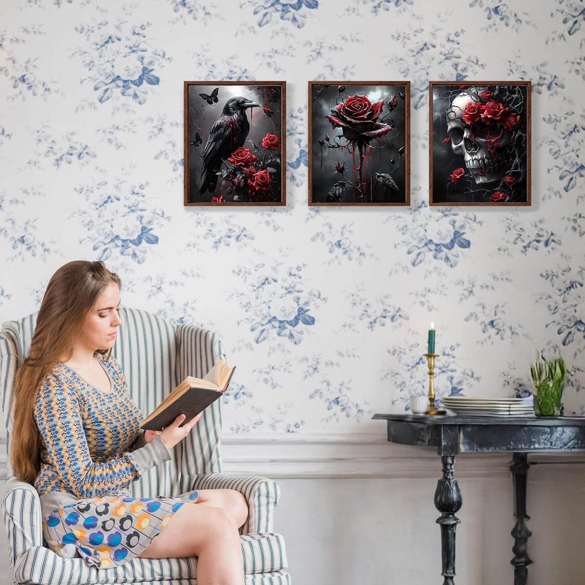 Woman reading a book in a striped armchair with three framed Halloween-themed diamond art prints on the wall