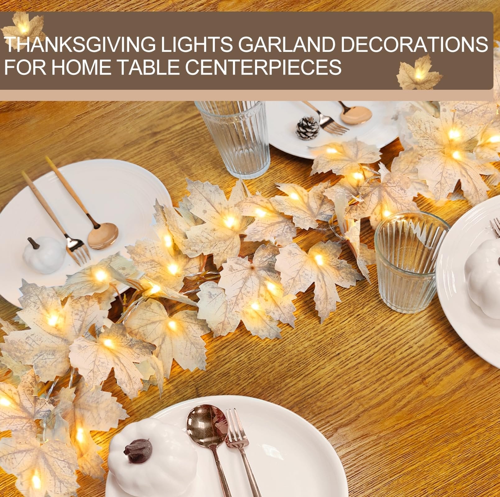 Lighted maple leaf garland with warm white LEDs draped across a wooden table setting with plates and pumpkins
