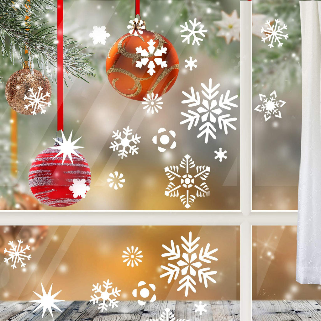 Christmas ornaments and snowflake decals on a window with a snowy background and pine branches