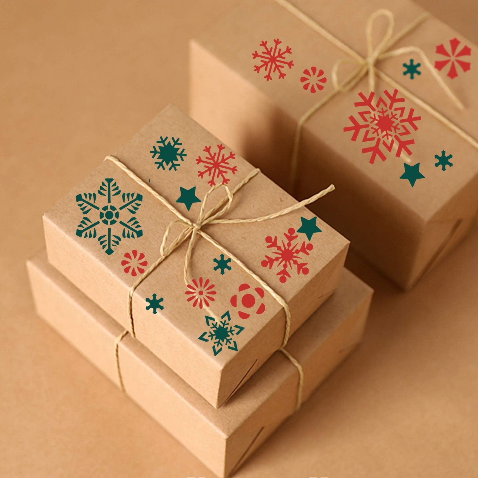 Christmas gift boxes decorated with red and teal snowflake and star stencils.