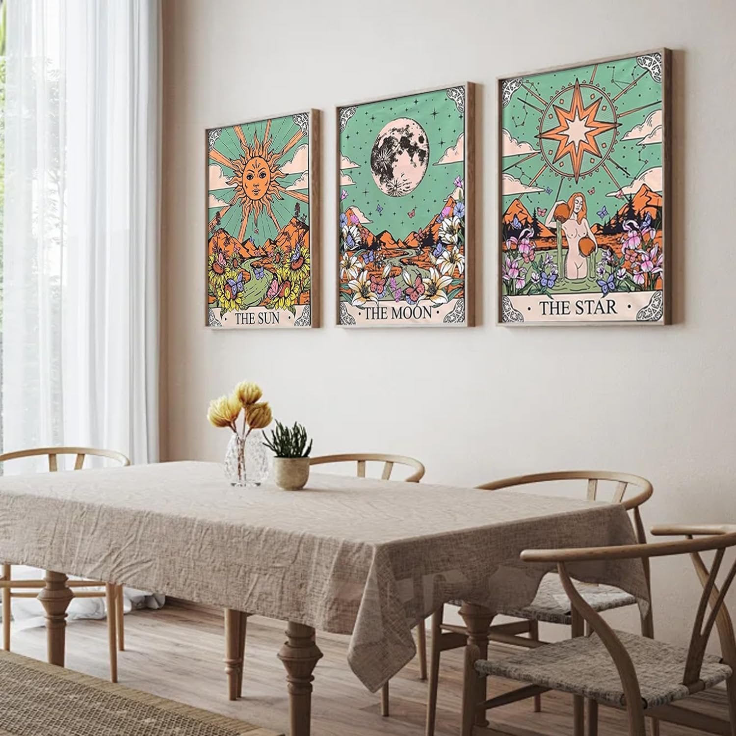 Three framed tarot-themed diamond art paintings of the Sun, Moon, and Star hanging on a wall above a dining table.