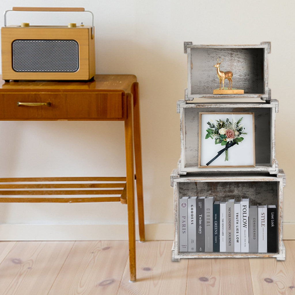 Three rustic wooden crates stacked, with decorative items and books inside. A vintage radio sits on a wooden table to the left.