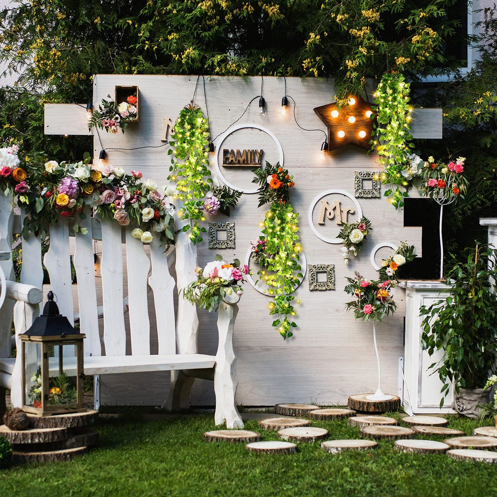 Decorated outdoor scene with hanging artificial ivy vines with fairy lights, flowers, and wooden letters spelling 'FAMILY' and 'MR'.