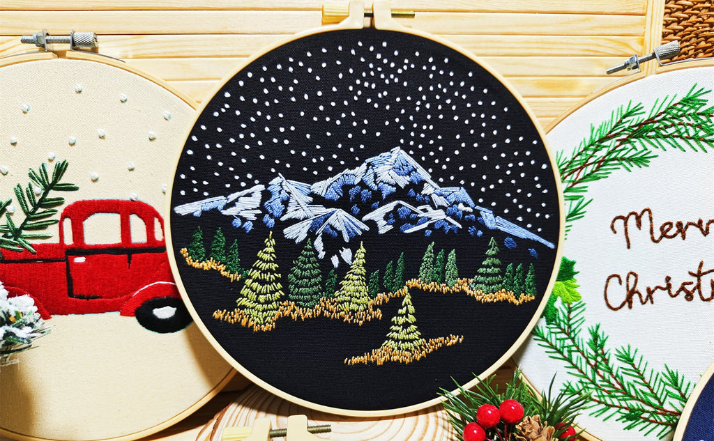 Three embroidery hoops with Christmas designs: a red truck, snowy mountains, and 'Merry Christmas' text.