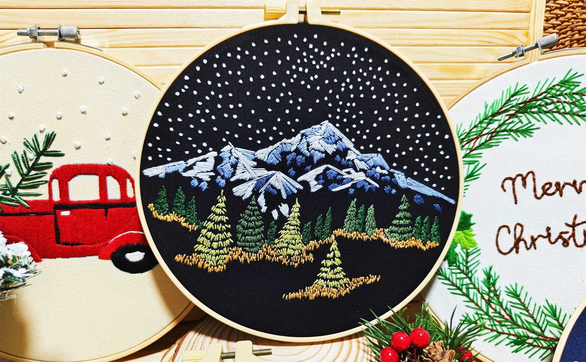 Three embroidery hoops with Christmas designs: a red truck, snowy mountains, and 'Merry Christmas' text.