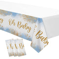 Dusty blue baby shower tablecloth with gold glitter accents and 'Oh Baby' text, shown draped over a table with three individually wrapped tablecloths in the foreground.