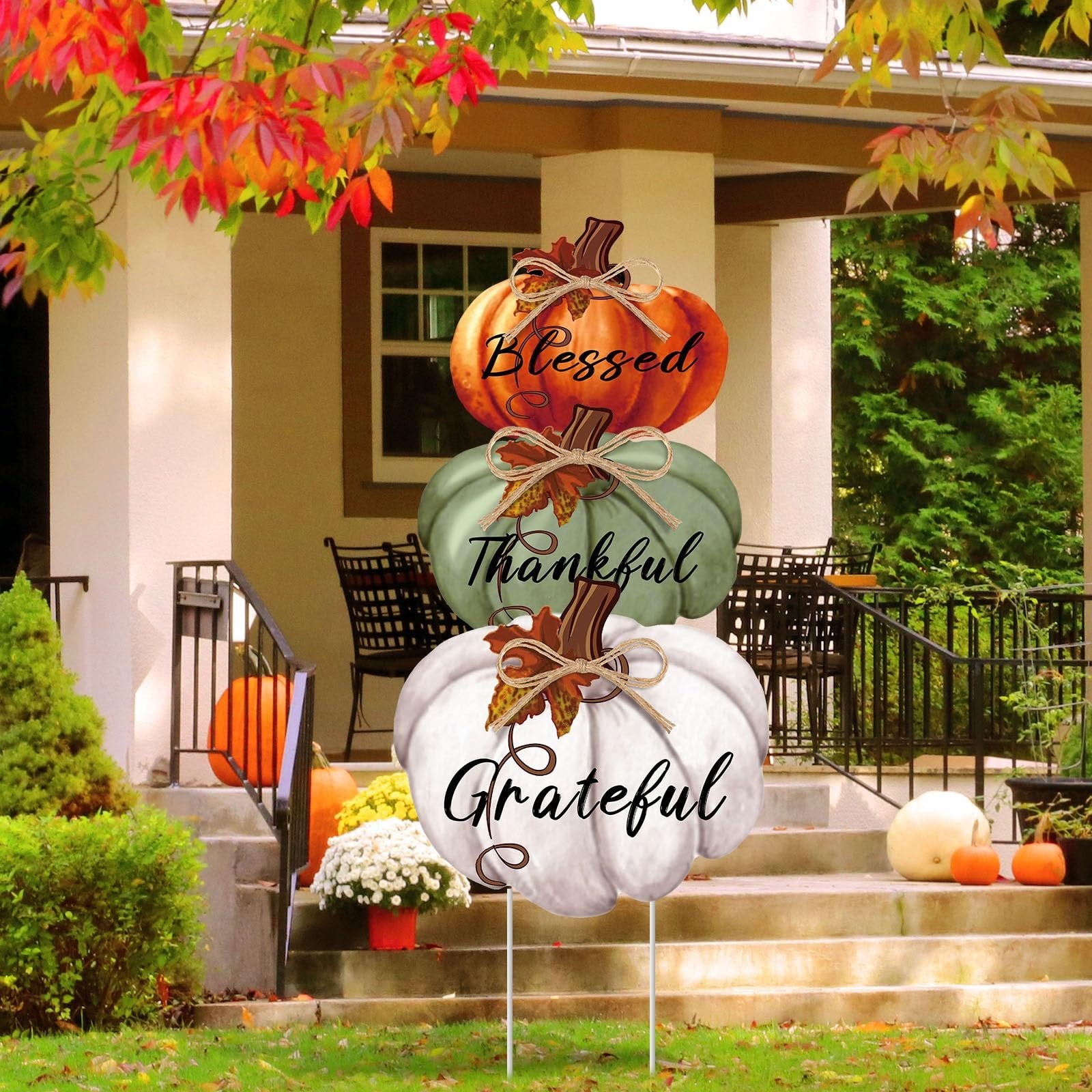 Stackable Thanksgiving pumpkin yard sign with Blessed, Thankful, Grateful text, displayed on a porch with autumn foliage.