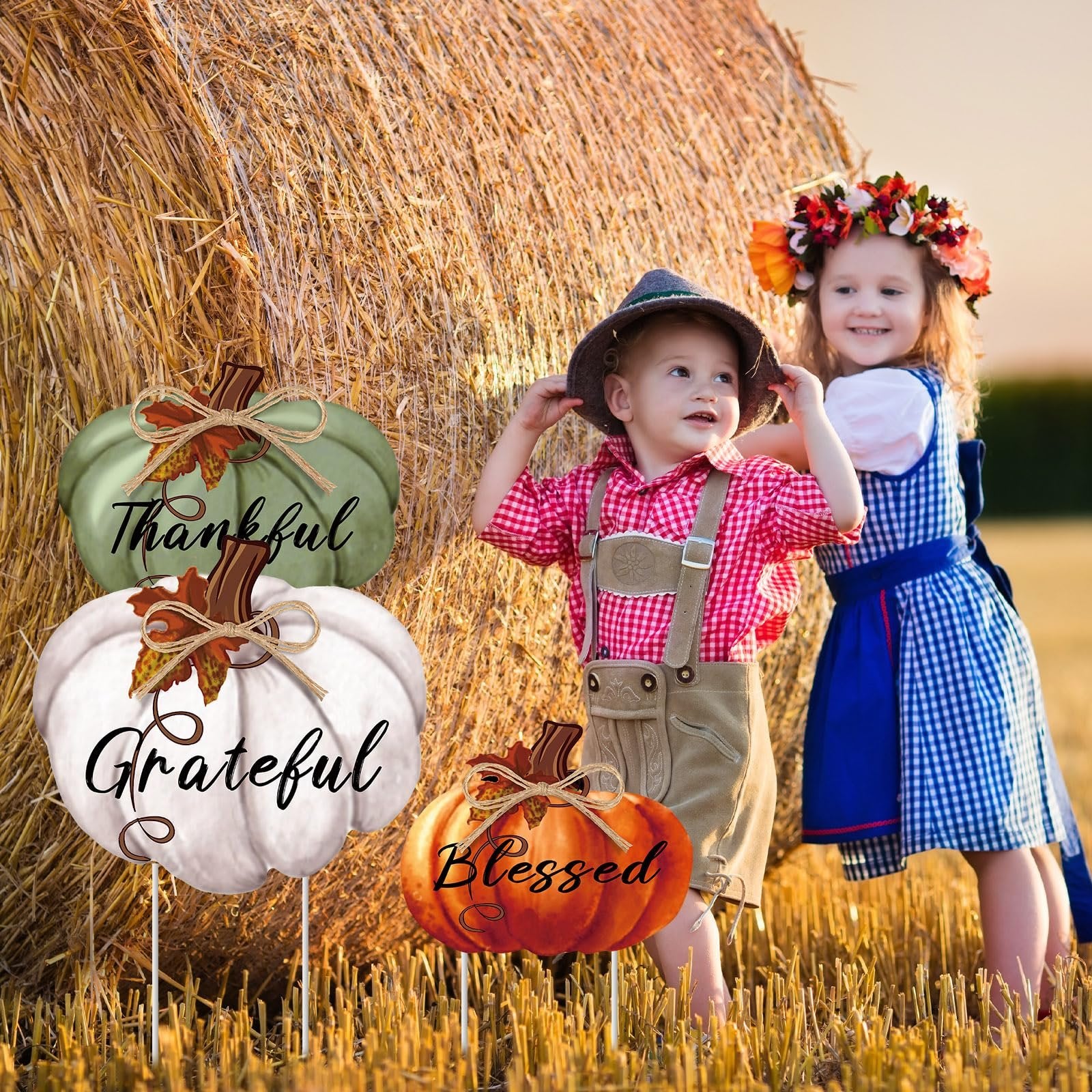 Three Thanksgiving pumpkin yard stakes with words Thankful, Grateful, and Blessed, in a field with two children.