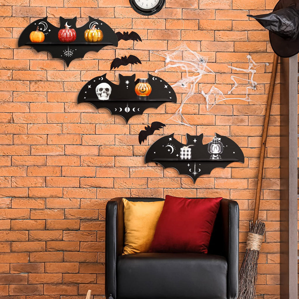 Three black bat-shaped shelves with Halloween decorations displayed on a brick wall above a black sofa.