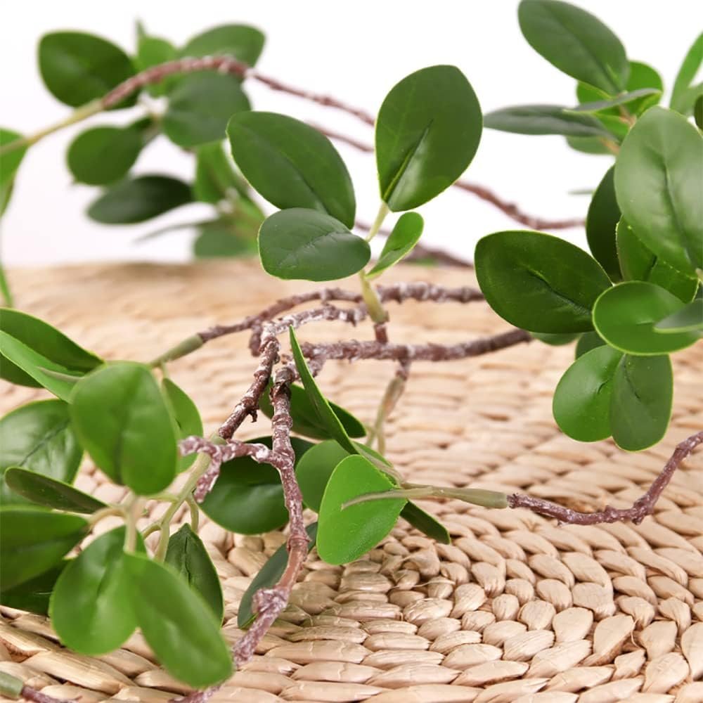 Artificial eucalyptus branches with green plastic leaves on a woven mat