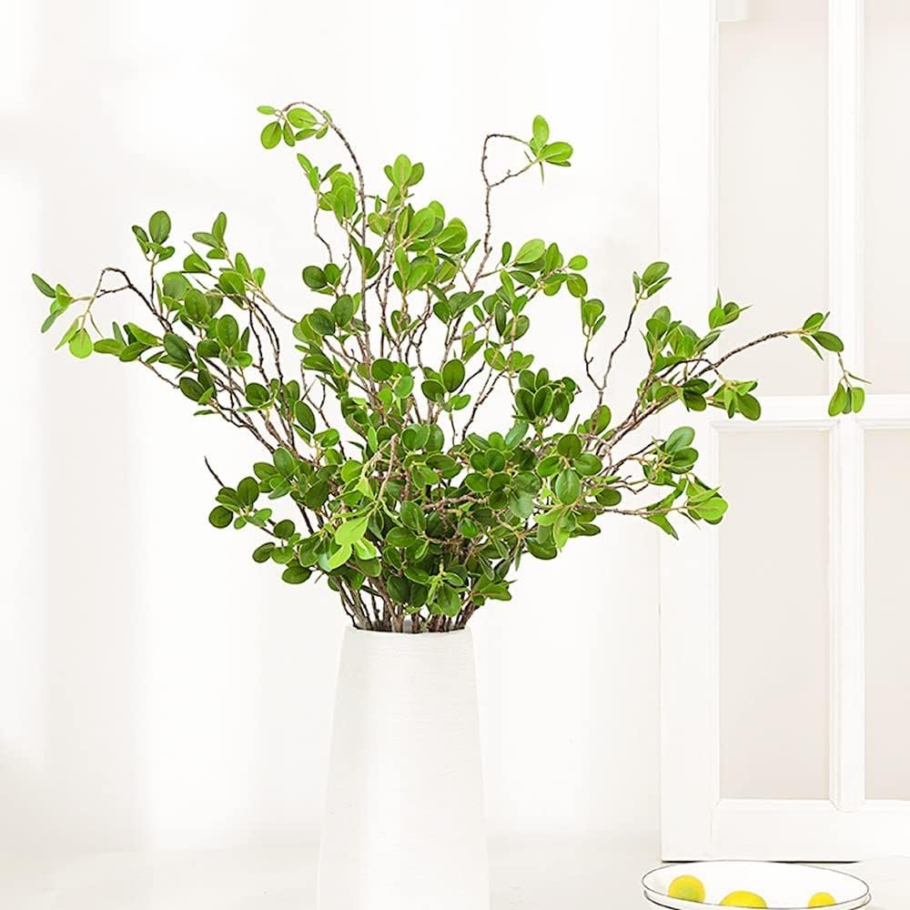 Artificial eucalyptus branches with green leaves in a white vase against a white background.