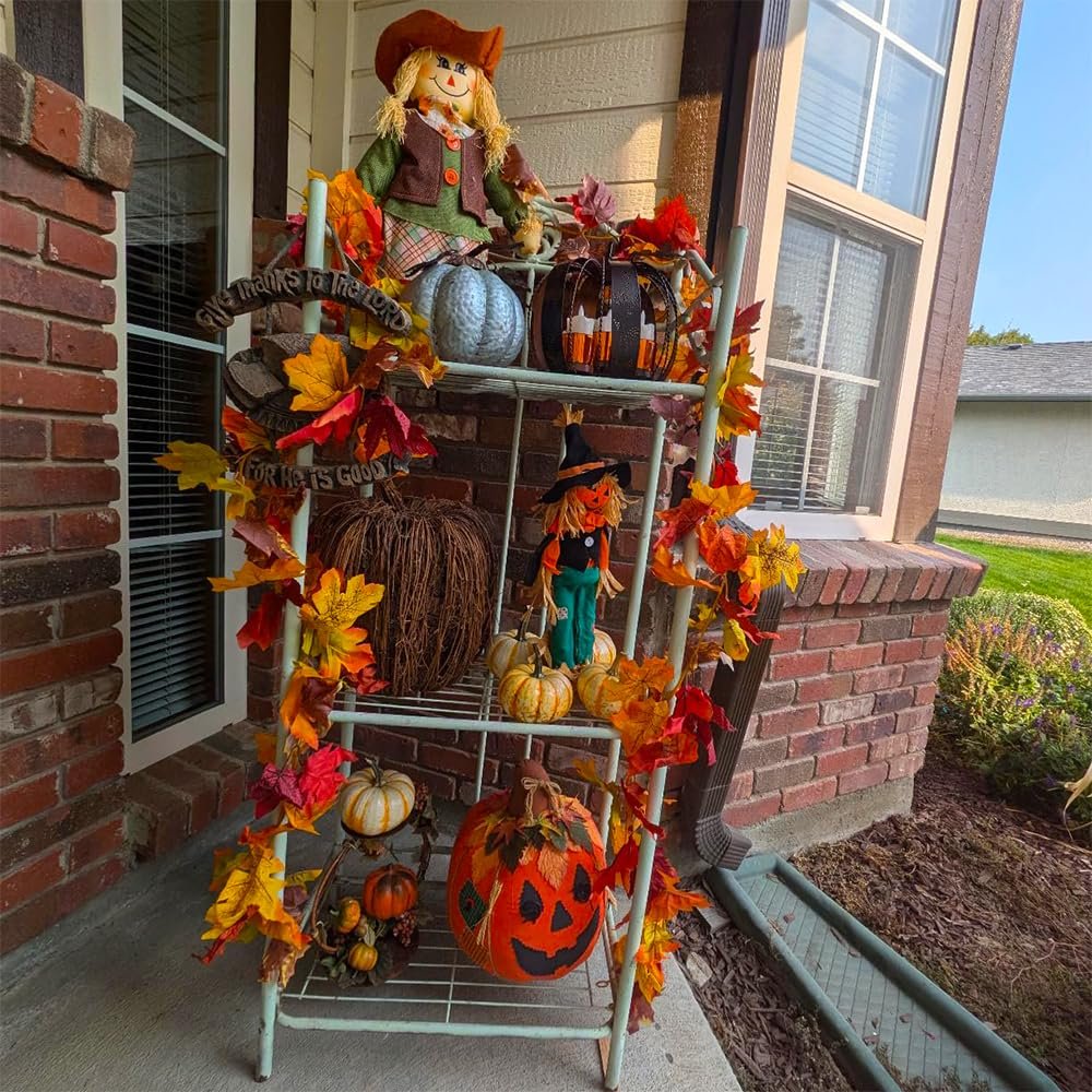 Fall harvest display on a tiered shelf with scarecrows, pumpkins, and faux maple leaf garlands.