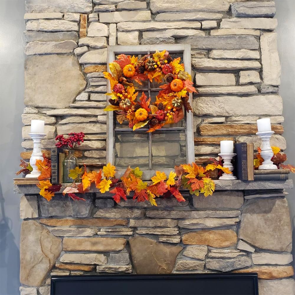 Autumn wreath and garland with pumpkins and maple leaves displayed on a stone fireplace mantel with candles and books.