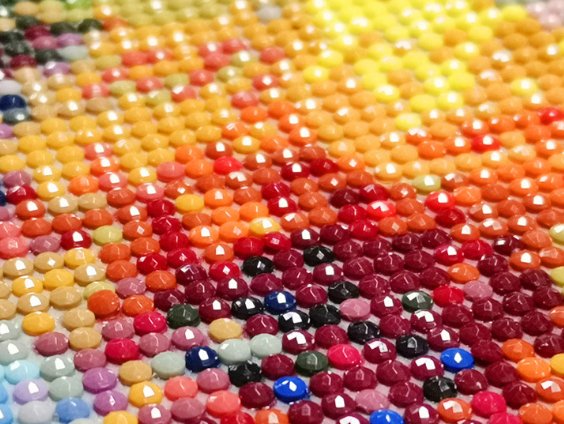 Close-up of a diamond painting bookmark with colorful rhinestones arranged in a sunflower pattern.