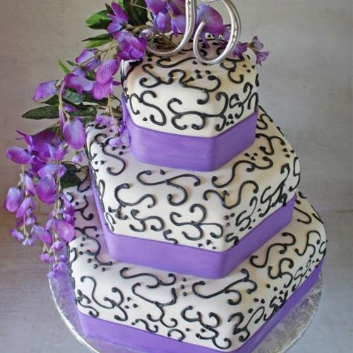 Three-tier square cake decorated with purple ribbon and black scrollwork, topped with purple flowers and a silver '50' topper.